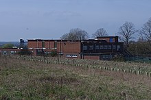 Red brick military building shown from the corner set in a field