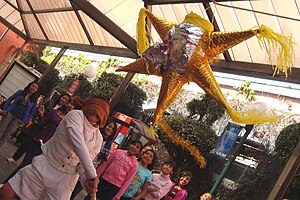 Children smashing a traditional star-shaped pinata in a pre-posada party in Mexico City. Rompiendo la pinata.JPG