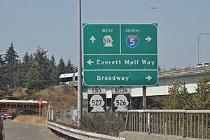 A highway sign with arrows and labels for streets in various directions