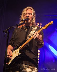 Thobbe Englund zpívající do mikrofonu a hrající na kytaru v roce 2012