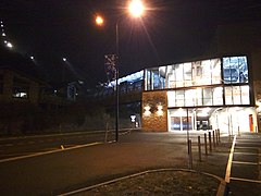 Photographie de nuit de la gare de départ avec des fenêtres éclairées et des lampadaires.