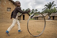 Boy playing hoop rolling in DRC Boy playing with a hoop in the streets of Pinga, RDC.jpg