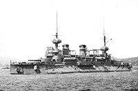 Foto de un buque de guerra anclado, visto desde el lado de babor.