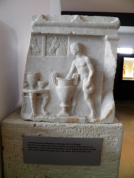Tập_tin:Framentuary_votive_relief_representing_a_youth_ladling_wine_for_a_krater_and_a_round_table_with_vases,_from_the_Agora,_end_of_4th_c._BC,_Archaeological_Museum,_Pella_(7065345633).jpg