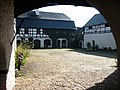 Vierseithof mit Torhaus, Scheune, kleinem Wohnhaus und großem Wohnstallhaus, Hofpflasterung, Einfriedungsmauern, Wassertrog im Hof und umgesetzter alter Schmiedewerkstatt (Denkmalschmiede Höfgen)