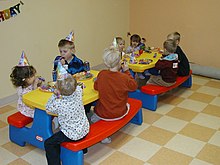 Children wearing rainbow party hats sitting at a rainbow table