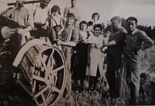 Grupo de maquisards de Alsacia y Lorena que participan en la cosecha de la finca Grandou con un tractor de ruedas de hierro y las mujeres y los niños de la familia