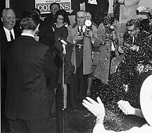 Mayor Collins (upper left) speaks to reporters after his victory Mayor John F. Collins being photographed by reporters as unidentified men and women throw confetti at re-election campaign party (10290589194) (crop1).jpg