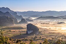 Planina plná světla se zbytkovými mlhami obklopená zalesněnými horami.