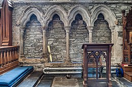 Photographie de quatre niches permettant de s'asseoir, creusées dans le mur intérieur d'une église médiévale.