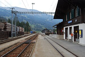 Two-story building with gabled roof next to three railway tracks and two platforms