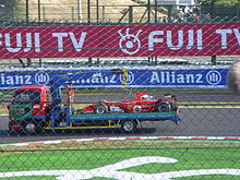 Michael Schumacher's Ferrari is returned to the pits after an engine failure cost him the race lead, and handed Fernando Alonso a ten-point advantage in the Drivers' Championship with one race remaining. Schumacher car Suzuka 2006.jpg