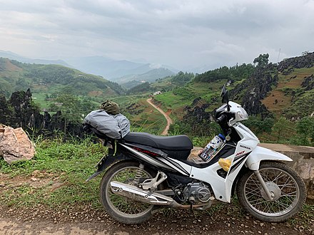 A typical rentable motorbike with plateaued crop fields in the background.