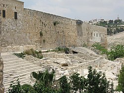 The long southern wall of Jerusalem's Temple Mount rises above two flights of stone steps between which are some low ruins
