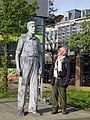 Een man van normaal postuur kijkt naar het beeld van Rigardus Rijnhout.