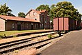 Blick über die Laderampe auf historische Waggons und das Bahnhofsgebäude