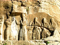 سنگ‌نگارهٔ «دیهیم‌ستانیِ» اردشیر از اهورامزدا، اردشیر ایستاده در پیشاپیش ملازمانش، شهر گور (فیروزآباد کنونی)