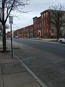 Photo d'une rue de Baltimore ressemblant à celles montrées dans la série avec des constructions en briques rouge.
