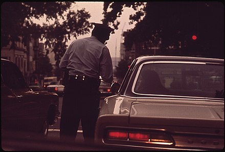 A Metropolitan Police Department of the District of Columbia officer ticketing a motorist for a traffic violation, 1973
