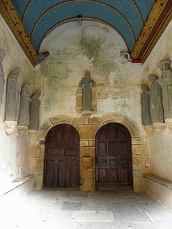 Inside the south porch with a view of the two doors accessing the church. Note the carved sablières at the top of the wall and above the statues of the apostles.