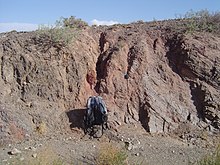Salmon-colored fault gouge and associated fault separates two different rock types on the left (dark gray) and right (light gray). From the Gobi of Mongolia. FaultGouge.JPG