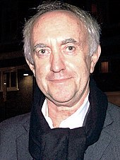 Jonathan Pryce olhando para a câmera.