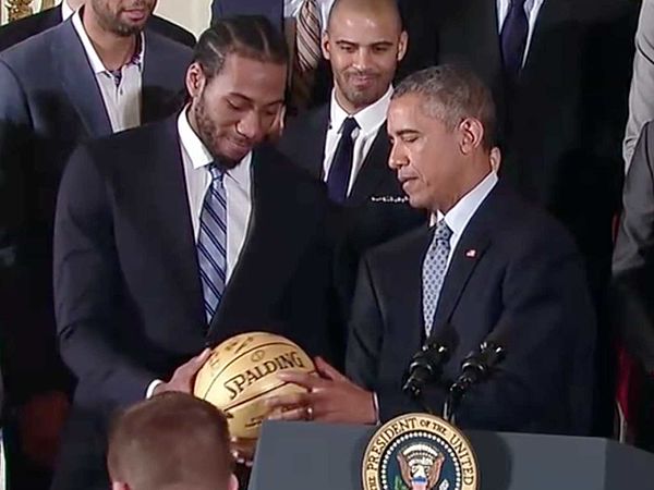 Leonard handing a signed ball to President Barack Obama at a White House ceremony honoring the Spurs team that won the 2014 NBA championship