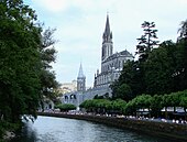 Pèlerinage de Lourdes en été avec vue des sanctuaires à droite, du château fort en fond et du gave de Pau.