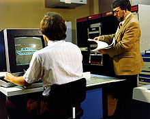 Mike Muuss (nalevo) u počítače PDP-11 s programem BRL-CAD při vývoji prototypu tanku M1 Abrams okolo roku 1980