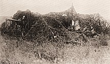Canon de 75 modele 1897 of Battery E, 119th Field Artillery Regiment during shelling of the village of Fismettes. Poorly camouflaged gun of Battery E, 119th Field Artillery Regiment during shelling of the village of Fismettes, north of the Vesle River during the Oise-Aisne Offensive in August 1918.jpg