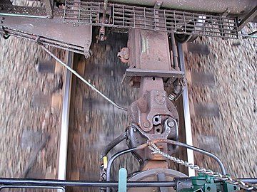 Standard AAR Type E couplers in a freight train. The upper coupler is bottom-operated, while the near coupler (on the locomotive) is top-operated by the chain.