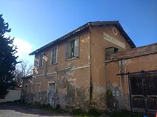 Il fabbricato viaggiatori della stazione di Cagliari-Pirri nel 2019, oramai abbandonato. Nella facciata laterale si legge il nome precedente della fermata: Monserrato-Pirri.