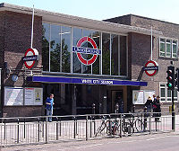 A brown-bricked building with a rectangular, dark blue sign reading "WHITE CITY STATION" in white letters all under a light blue sky