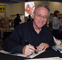 Zeck smiling at a table with a drawing in front of him