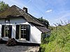 Gepleisterde, tegen de dijkvoet gebouwde boerderij