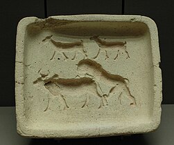 Forma de pão, representando duas cabras e um leão atacando uma vaca (terracota do início do segundo milênio a.C., do palácio real de Mari)