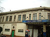 Um edifício de cor castanha com janelas de moldura castanha e uma placa a dizer "METROPOLITAN EDGWARE ROAD STATION RAILWAY" em letras castanhas