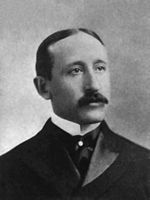 Portrait en noir et blanc d’un homme blanc brun et moustachu.