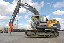 An excavator-mounted hydraulic jackhammer being used to break up concrete. Note it is adding the weight of the forward half and boom of the machine to aid the driver's effectiveness Excavator jackhammer.jpg