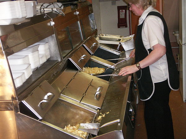 A chef cooking traditional British fish and chips in a deep fryer