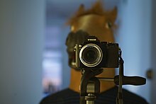 Vue d’un appareil photo ne prenant pas la tête de cheval en arrière-plan flou, mais visant le preneur de la présente image.