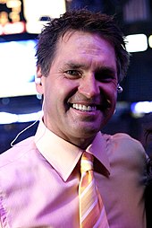 Kelly Hrudey smiling in a pink button-up shirt with a tie on
