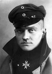 A young male in flying uniform, with a medal around his neck.