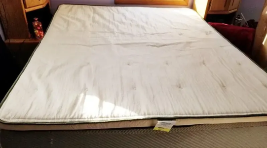 A mattress topper (white) on a boxspring mattress (grey). Mattress toppers are generally structurally similar to futons, are often made of similar materials, and (in the case of twin-bed toppers) have similar dimensions. Note the tufting.