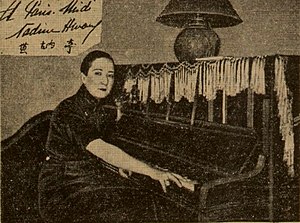 Nadine Hwang ist sitzend an einem Klavier zu sehen. Sie schaut in die Kamera und trägt kurzes Haar. Die Fotografie ist in Sepia.