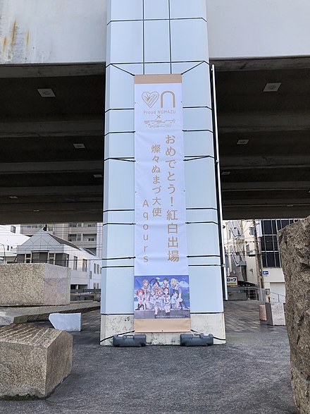 A banner posted at Numazu City Hall celebrates the fictional idol group Aqours, from the anime series Love Live! Sunshine!!, for being accepted as a participating performer in the 2018 Kōhaku Uta Gassen.