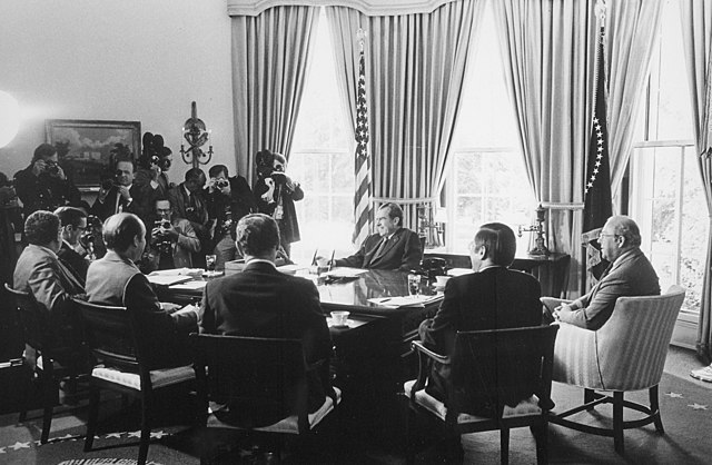 An Oval Office meeting of Nixon administration economic advisors and cabinet members on May 7, 1974. Clockwise from Richard Nixon: George Shultz, Jame