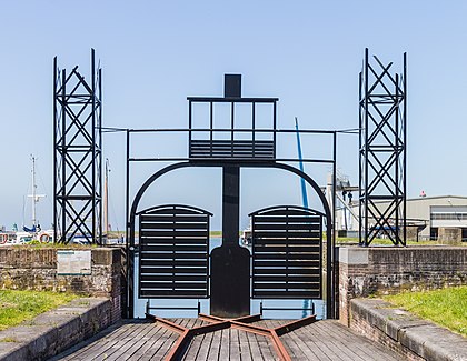 Réplica do porto ferroviário Pontgat Spoorhaven (2015), uma escultura projetada pelo arquiteto Joop van der Woude em Stavoren, Súdwest-Fryslân, Países Baixos. A partir de 1900, as composições funcionaram sem problemas em Stavoren na balsa em direção a Enkhuizen. A ligação de frete era muito usada, mas caiu em desuso na década de 1930. Em 1936 a balsa realizou a última travessia. O edifício foi demolido em 1950. Esta réplica é uma recordação dos habitantes locais dessa conexão especial. (definição 4 277 × 3 313)