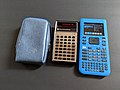A TI-30 next to its carrying case, with a modern TI nSpire beside it