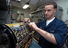 An Aviation Electrician's Mate replacing a silicon-controlled rectifier (SCR) on an F/A-18 Hornet generator US Navy 040104-N-7090S-001 While conducting maintenance, Aviation Electrician's Mate Airman John O'Brien from Lindon, N.J., places a fuse on a generator used in an F-A-18 Hornet.jpg